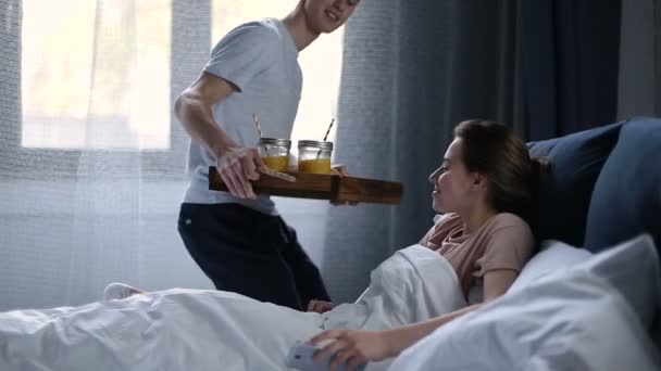 Χαμογελαστά ζευγάρι κατοχής του προγεύματος στο κρεβάτι πρωί — Αρχείο Βίντεο