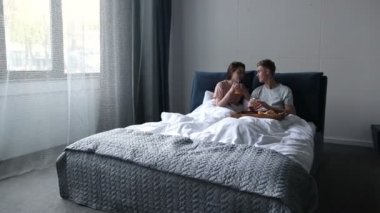 Genç çift evde yatakta kahvaltı paylaşımı