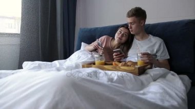Şirin çift dalga köpüğü ağ ile yatakta akıllı telefonlar