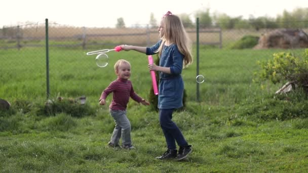 Glad söt barn som leker med bubblor i gården — Stockvideo