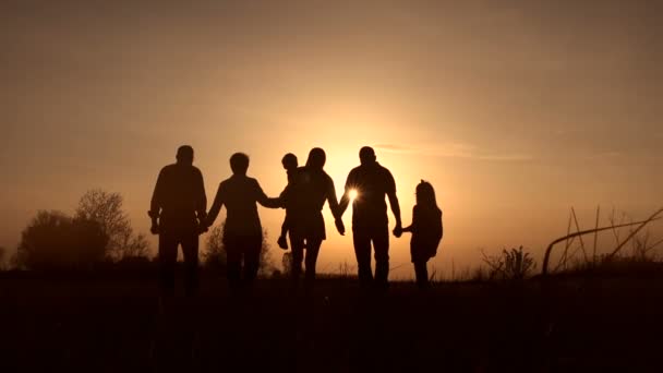 Trois générations de famille marchent dans la prairie au coucher du soleil — Video