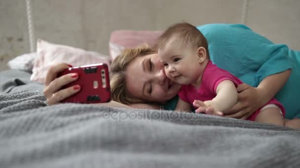 Мать и ребенок делают селфи с телефоном в постели — стоковое видео