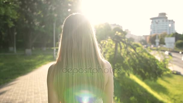 Charmante blonde Frau, die bei Sonnenuntergang auf dem Bürgersteig läuft — Stockvideo