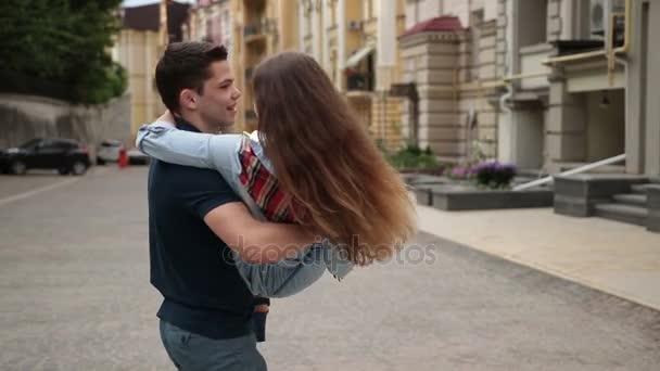 Красивий молодий чоловік тримає дівчину в руках — стокове відео