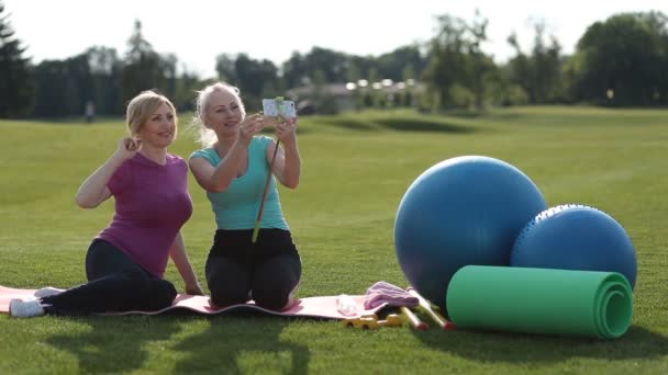 Sonrientes mujeres senior fitness que selfie en Parque — Vídeos de Stock