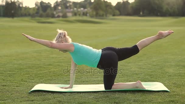 Attraktive erwachsene Frau praktiziert Yoga im Park — Stockvideo
