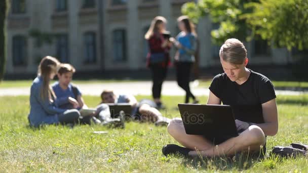 Beau étudiant masculin étudiant avec ordinateur portable dans le parc — Video