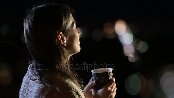Χαμογελαστή γυναίκα πίνοντας καφέ σε εξωτερικούς χώρους, τη νύχτα — Αρχείο Βίντεο