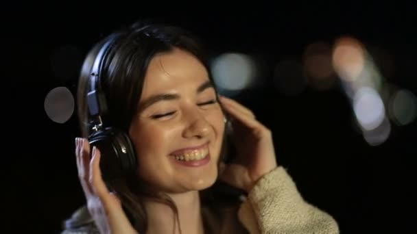 Chica escuchando música con auriculares en la noche — Vídeos de Stock