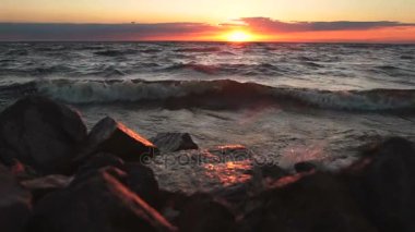 Kayalık bir sahil üzerinde kızıl gökyüzü. Gün batımı manzarası.