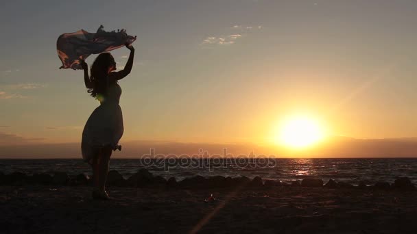 Donna gioiosa con sciarpa volante sulla spiaggia al tramonto — Video Stock