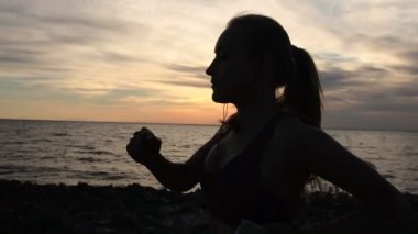 Gün batımında sahil üzerinde çalışan sportif fitness kadın