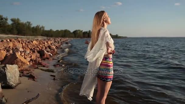 Женщина наслаждается свободой и жизнью на пляже на закате — стоковое видео