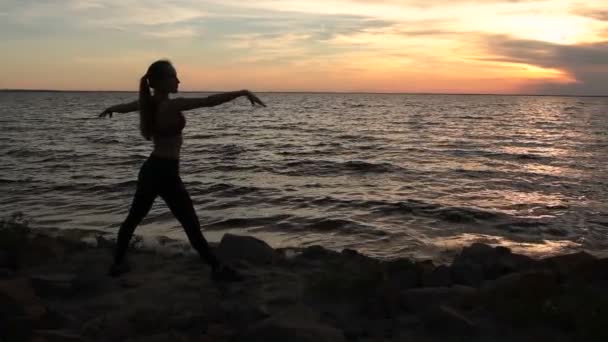 Mujer delgada ejercitando yoga guerrero posar en la playa — Vídeos de Stock