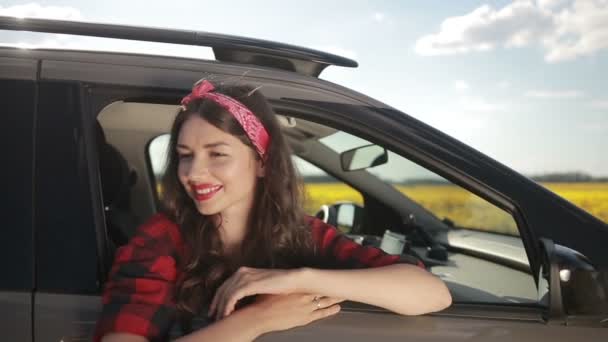 Jonge vrouw ontspannen op auto deur tijdens reis — Stockvideo