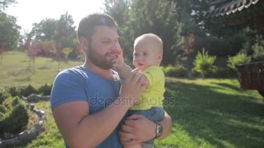 Parkta küçük oğlu tutan genç hipster baba