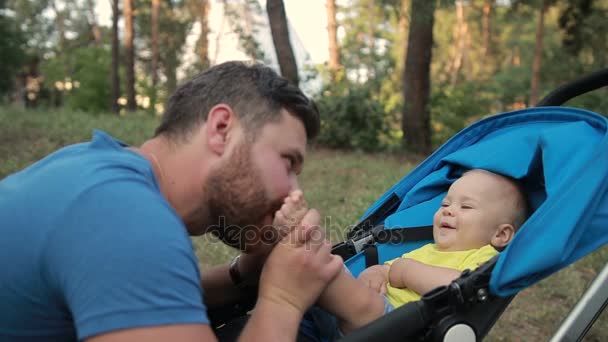 慈爱的父亲，亲他的宝贝儿子在公园里的脚 — 图库视频影像