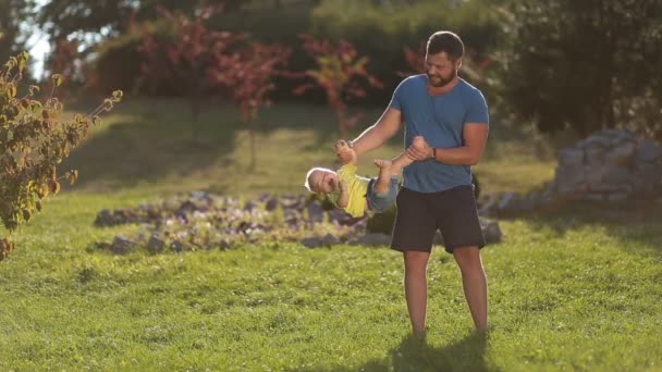 Веселый отец размахивает своим маленьким мальчиком в парке — стоковое видео