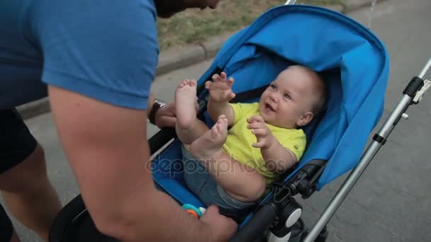 Любящий отец играет с малышом сыном в коляске — стоковое видео