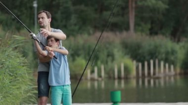 Genç çocuk babaları yardımıyla balık tutmayı öğrenme