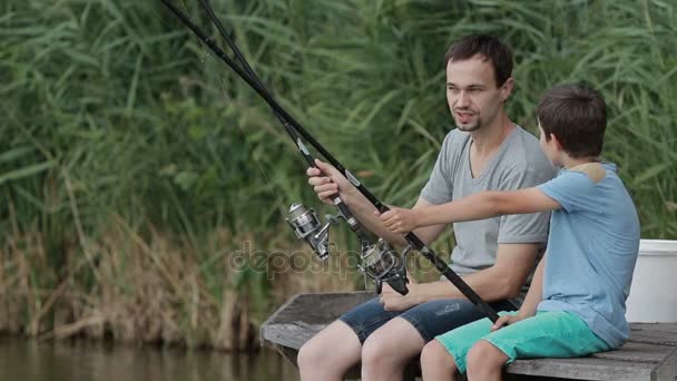 Positive father and son fishing together on pond — Stock Video