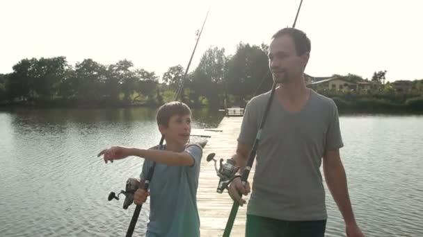 Ευτυχής μπαμπάς και γιος με βέργες Πηγαίνοντας Ψάρεμα σε λίμνη — Αρχείο Βίντεο