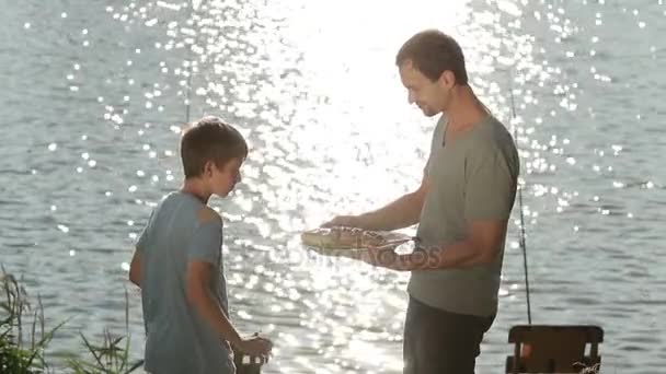 Fröhlicher Junge duftet nach gebratenem Fisch auf dem Grill — Stockvideo