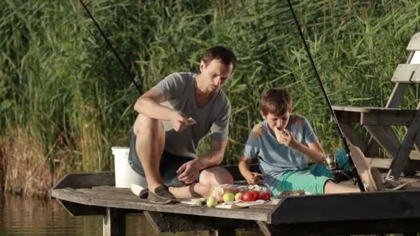 Famiglia godendo pasto in riva al lago durante la pesca — Video Stock
