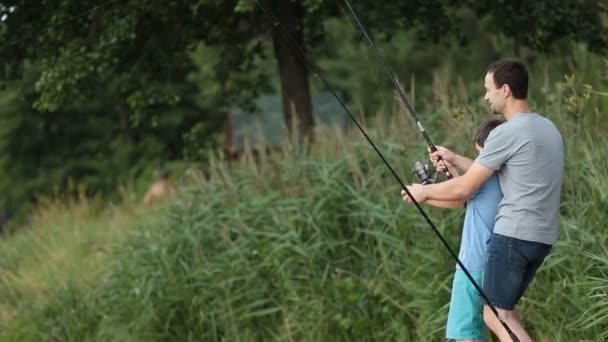 Aufgeregter Sohn und Vater fangen Fische am Teich — Stockvideo