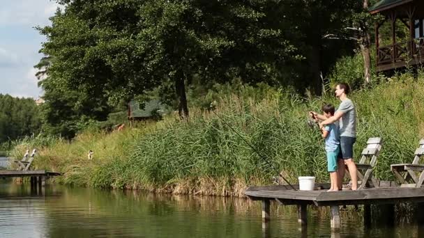Pai ensinando filho a pescar em lagoa de água doce — Vídeo de Stock
