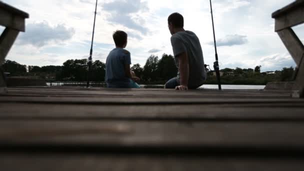 Расслабленные отец и сын сближаются во время рыбалки на озере — стоковое видео