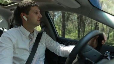 Arabanın içinde arama yapmak için eller ücretsiz aygıt kullanan adam