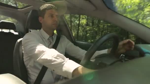 Красивый серьезный человек водит машину по сельской дороге — стоковое видео