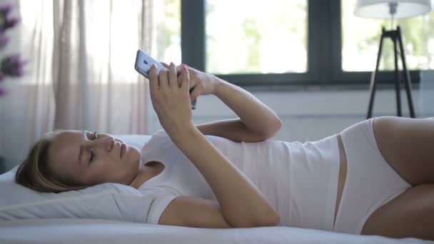 女人在床上检查社交应用程序与智能手机 — 图库视频影像