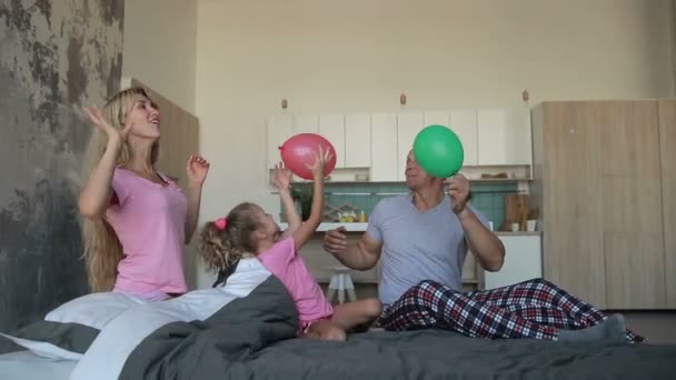 Glad familj spelar med ballonger på säng — Stockvideo