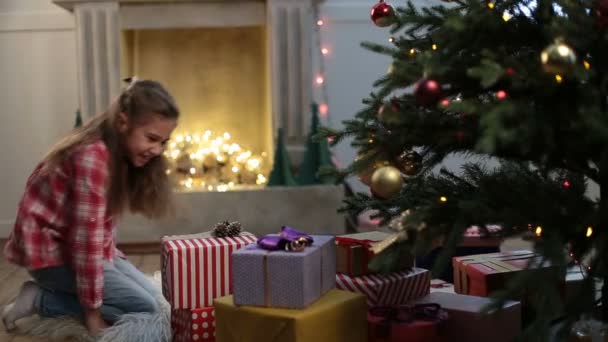 可爱的小女孩，寻找在圣诞树下的礼物 — 图库视频影像