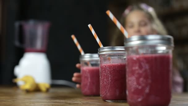 Vrolijke weinig meisje drinken smakelijke bessen smoothie — Stockvideo