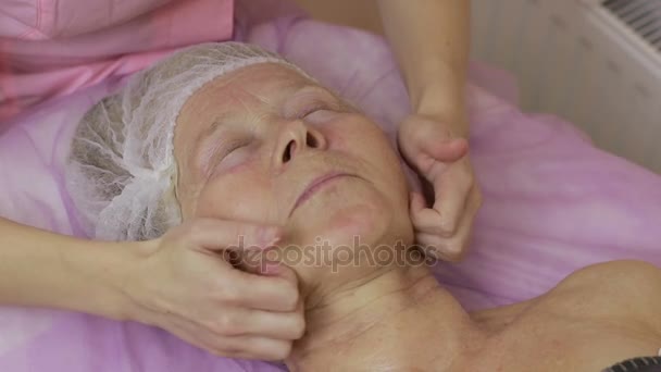 Female hands massaging senior womans face — Stock Video