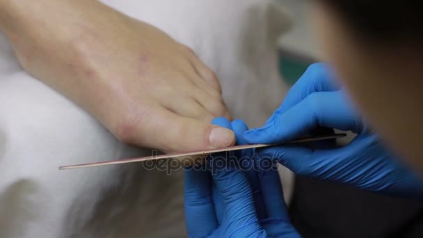 Beautician hands filing female toenail — Stock Video