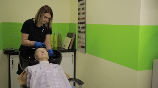 Старшая женщина проходит процедуру мойки волос в салоне — стоковое видео