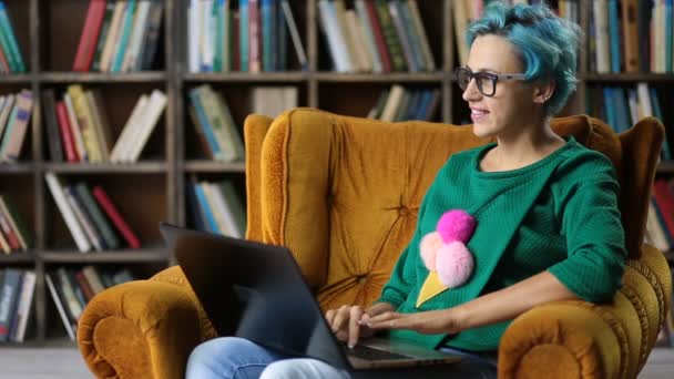 Menina hipster encantador digitando no laptop na biblioteca — Vídeo de Stock