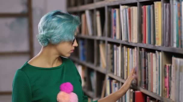Хипстерская девушка ищет книгу в книжном магазине — стоковое видео