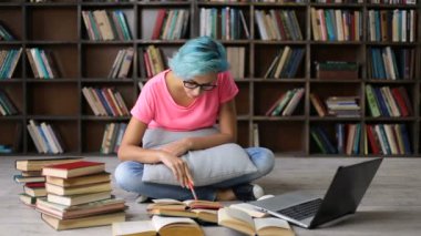 Kız öğrenci kitap ve dizüstü bilgisayar ile araştırma