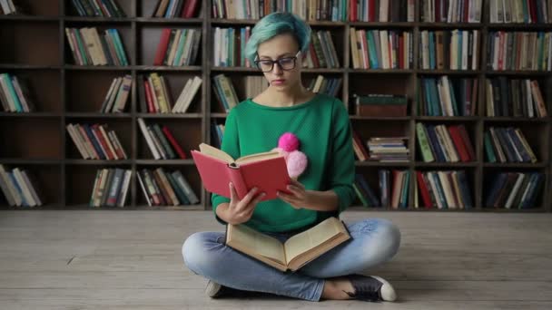 Jovem mulher de óculos lendo um livro interessante — Vídeo de Stock