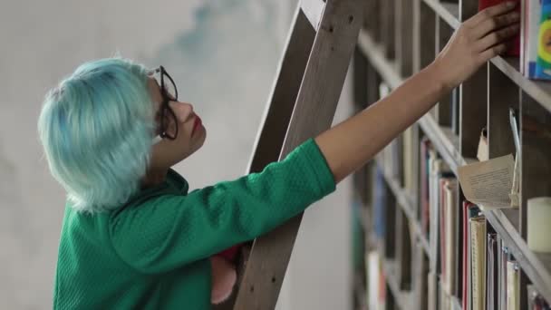 Молодий студент шукає книги на полицях — стокове відео