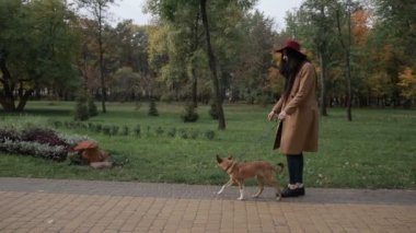 Genç kadın okşayarak köpek sonbahar Park gülümseyen