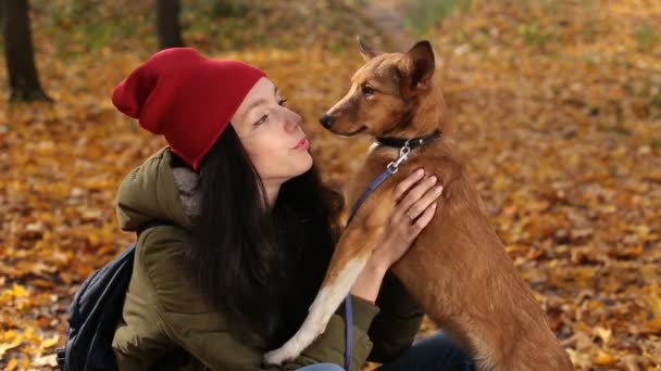 Hipster girl playing with her dog on autumn day — Stock Video