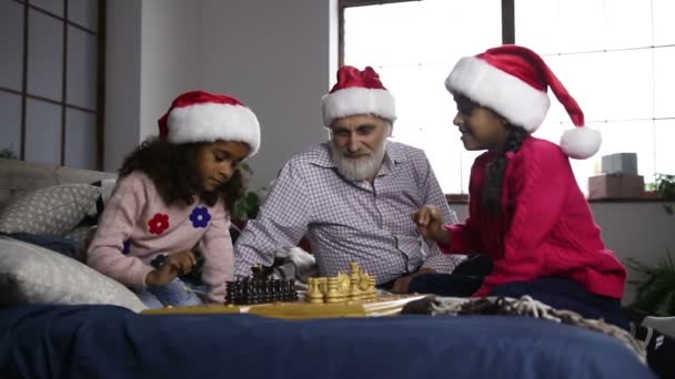 Dos hermanas de raza mixta jugando ajedrez en víspera de Navidad — Vídeos de Stock