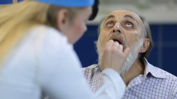 Hombre mayor en el médico revisando su garganta — Vídeo de stock