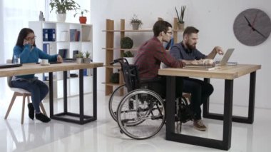 Ofiste çalışan tekerlekli sandalyede hipster adam